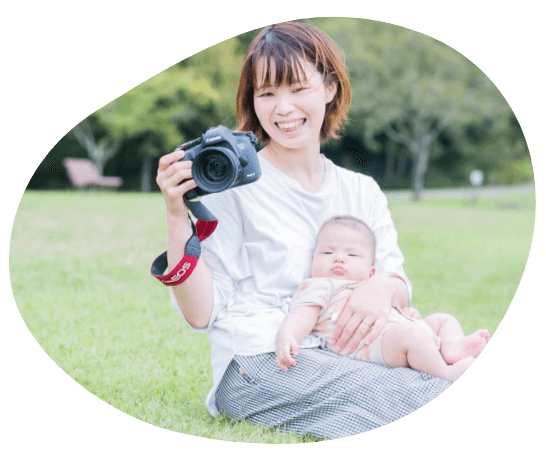 赤ちゃんと一眼レフのカメラを持った女性の卒業生